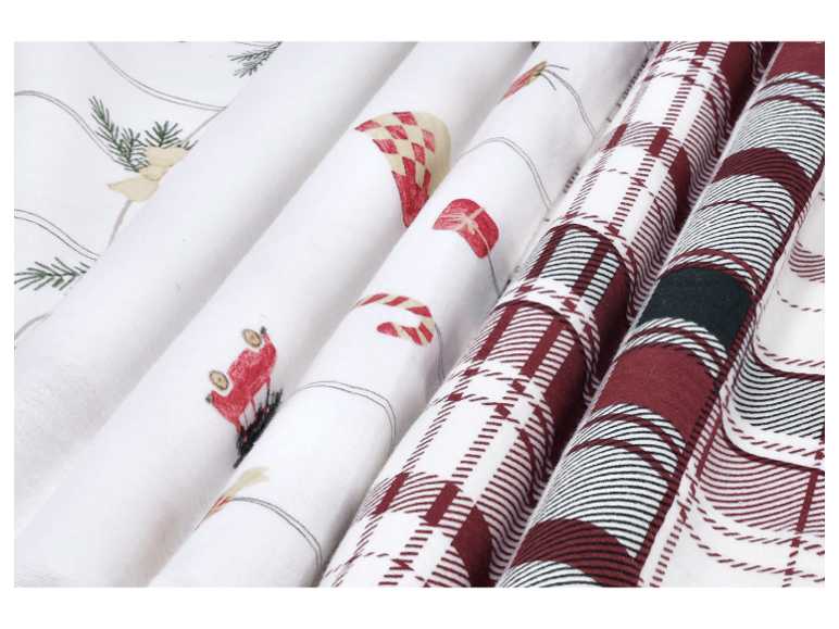 Nahaufnahme von gefalteten Stoffen mit Weihnachtsmotiven und Karomuster.
