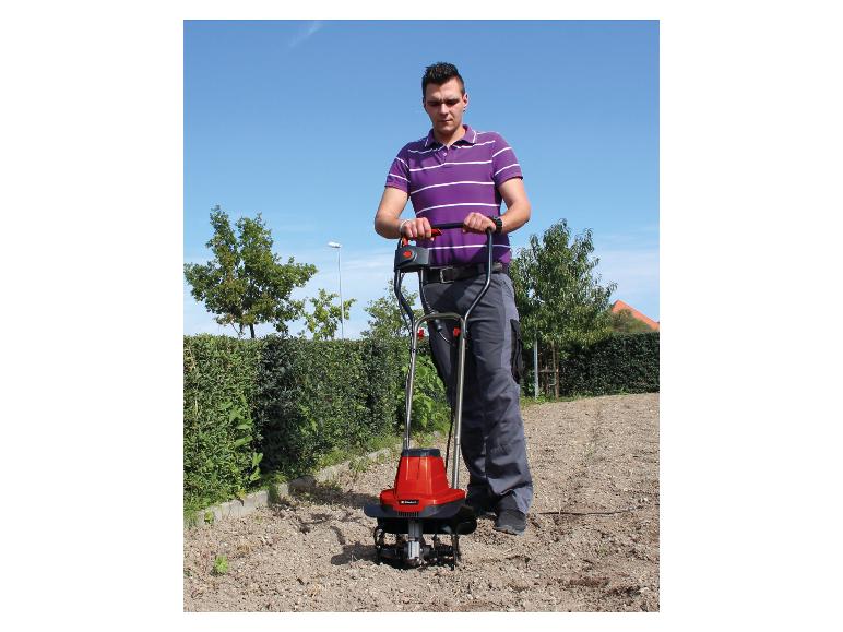 Mann benutzt eine rote Gartenfräse auf einem Schotterweg.