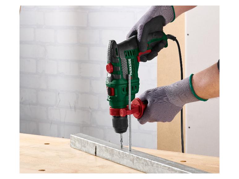 Mann in Handschuhen bohrt mit einer PARKSIDE Schlagbohrmaschine in einen Metallträger.
