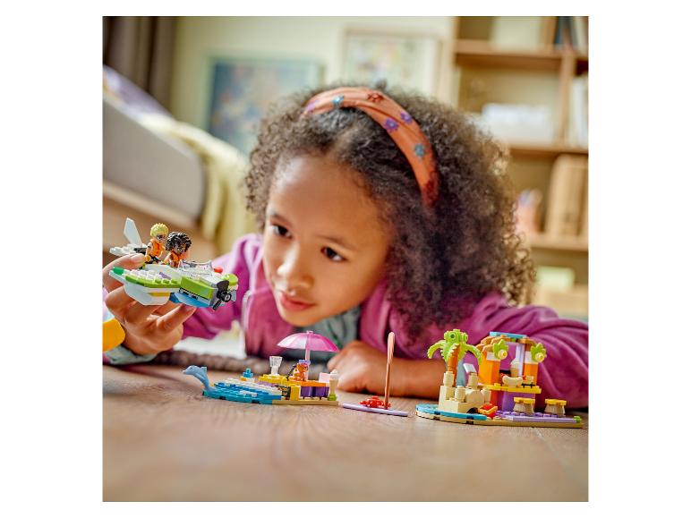 Mädchen spielt mit LEGO Friends Sets auf dem Boden.