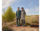 Mann und Frau in Regenjacken und Stiefeln stehen in der Natur.
