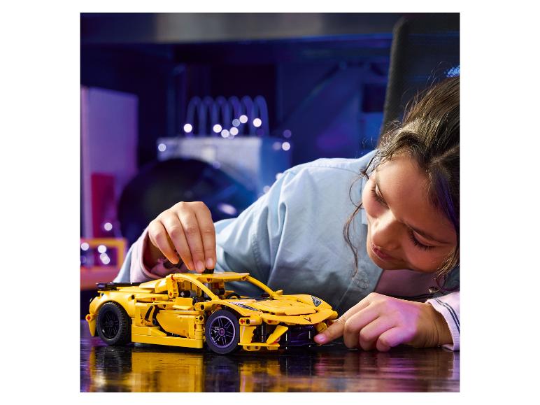 Ein Mädchen baut einen gelben Sportwagen aus Bausteinen zusammen.