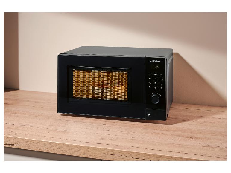 Schwarze Mikrowelle mit Digitalanzeige und Drehknopf auf einer Holztheke.