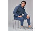 Mann in marineblauem Trainingsanzug und grauen Sneakern, auf einem Hocker sitzend.