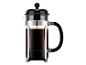 French Press Kaffeebereiter mit dunklem Kaffee und Kaffeesatz, schwarzem Deckel und Griff sowie Chromrahmen.