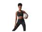 Frau in schwarzem Sport-BH und Leggings, die einen grauen Gymnastikball hält