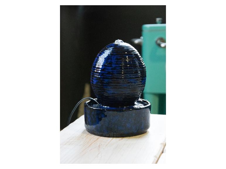 Blauer Keramik-Tischbrunnen mit Wasser, das über eine gerippte Oberfläche fließt.