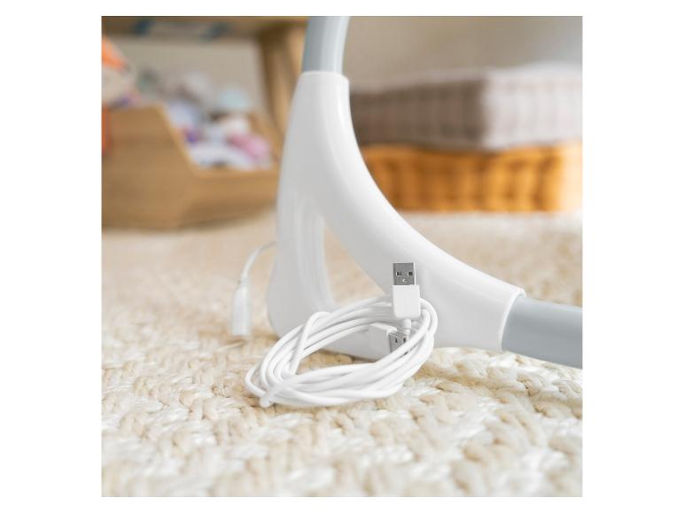 Weißes USB-Kabel und Ladegerät auf einem weißen Teppich, mit unscharfen Objekten im Hintergrund.