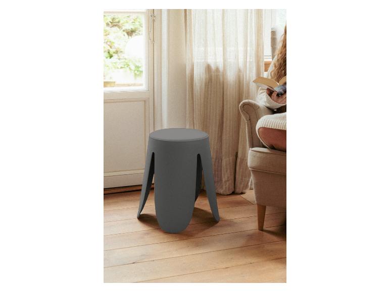 Ein niedriger grauer Hocker mit vier Beinen steht auf einem Holzboden.