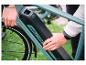 Mann entfernt Akku mit einem Schlüssel von einem grünen E-Bike.