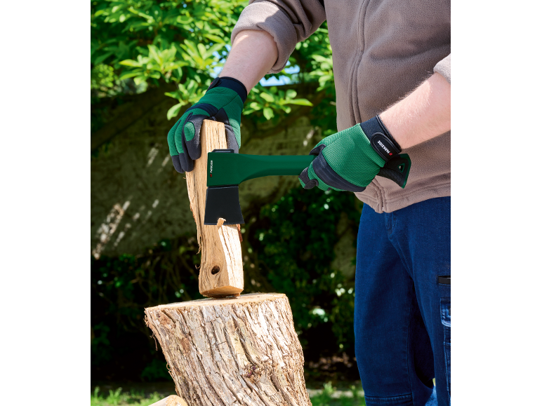 Person in grünen Handschuhen spaltet Holz mit einer grünen Axt auf einem Hackklotz.