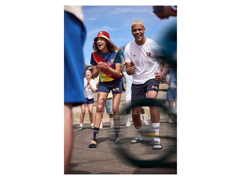 Menschen in Sportkleidung und Badelatschen mit Socken, die draußen jubeln.