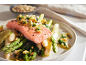 Gebackener Lachs mit Spargel, weißen Bohnen und Pinienkernen auf einem weißen Teller.