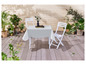 Weißer Tisch mit zwei Stühlen und einer weißen Tischdecke auf einer Holzterrasse.