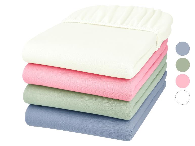 Stapel Spannbettlaken in Pastellfarben: Cremeweiß, Rosa, Mintgrün und Blau.