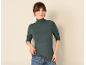 Frau in dunkelgrünem Ripp-Rollkragenpullover und blauer Jeans
