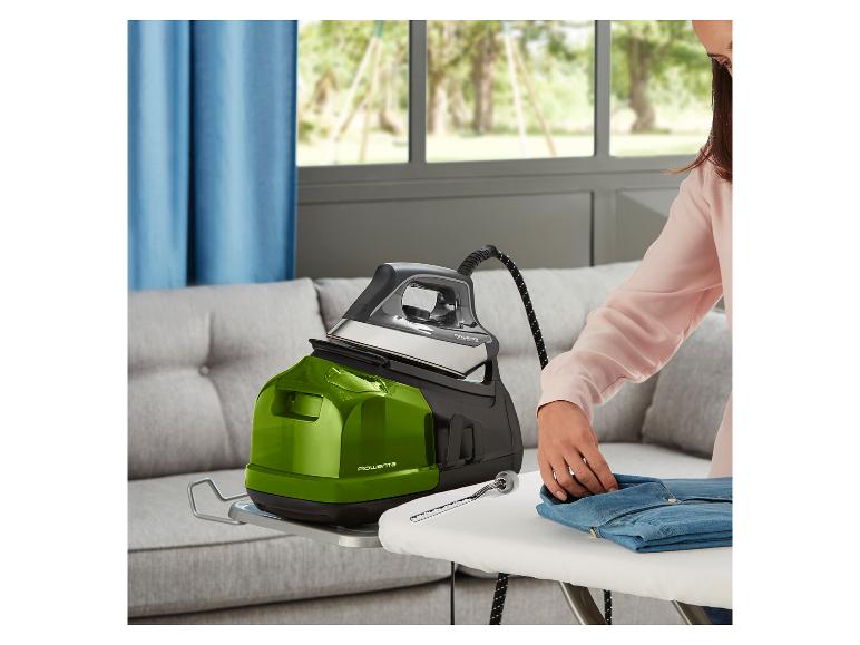 Eine Frau bügelt ein Jeanshemd mit einem grünen und schwarzen Rowenta Dampfbügeleisen auf einem Bügelbrett.