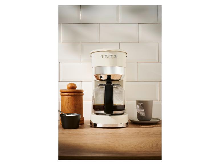 Eine cremefarbene Kaffeemaschine 1973 auf einem Holztisch.