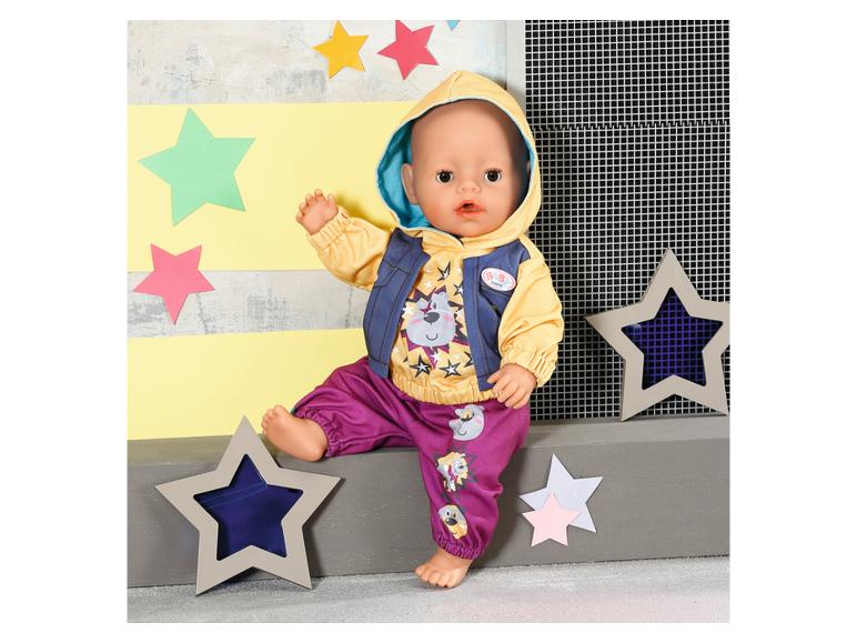 BABY born Puppe in gelbem Hoodie, lila Hose und blauer Weste, umgeben von Sternen.