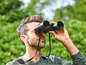 Ein Mann betrachtet die Natur durch ein Fernglas.