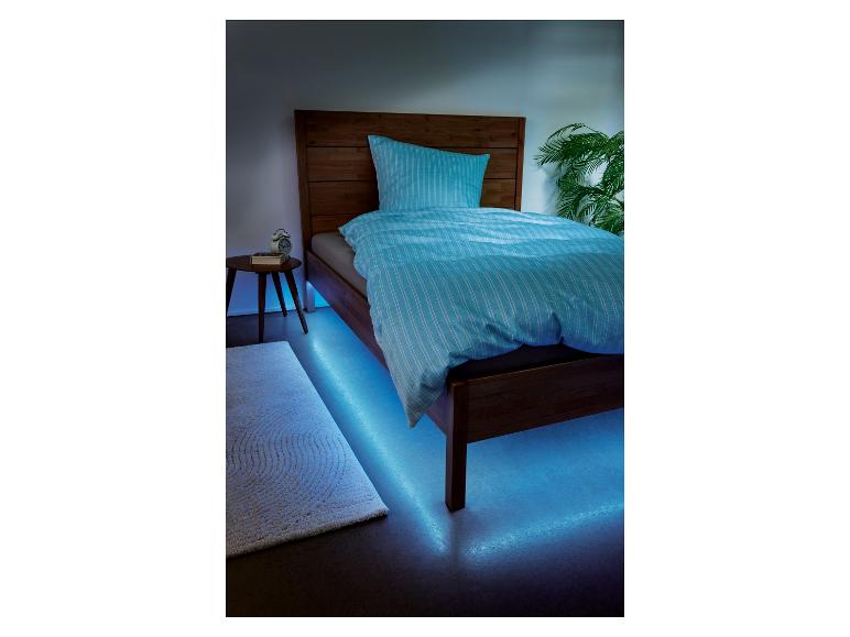 Ein Bett mit blauer Bettwäsche und LED-Beleuchtung.