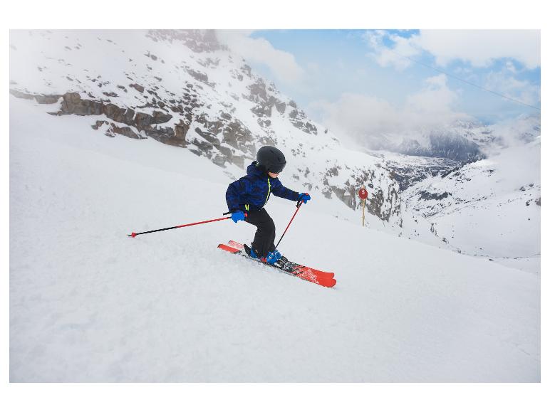 Kind in blauer Skiausrüstung und schwarzem Helm fährt einen verschneiten Berghang hinunter.