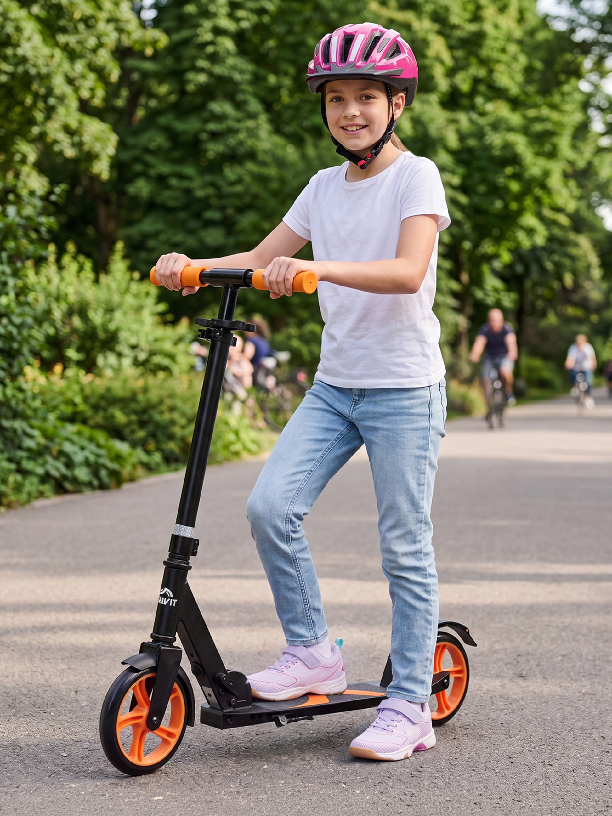Mädchen mit rosa Helm und schwarzem Roller mit orangefarbenen Rädern in einem Park.