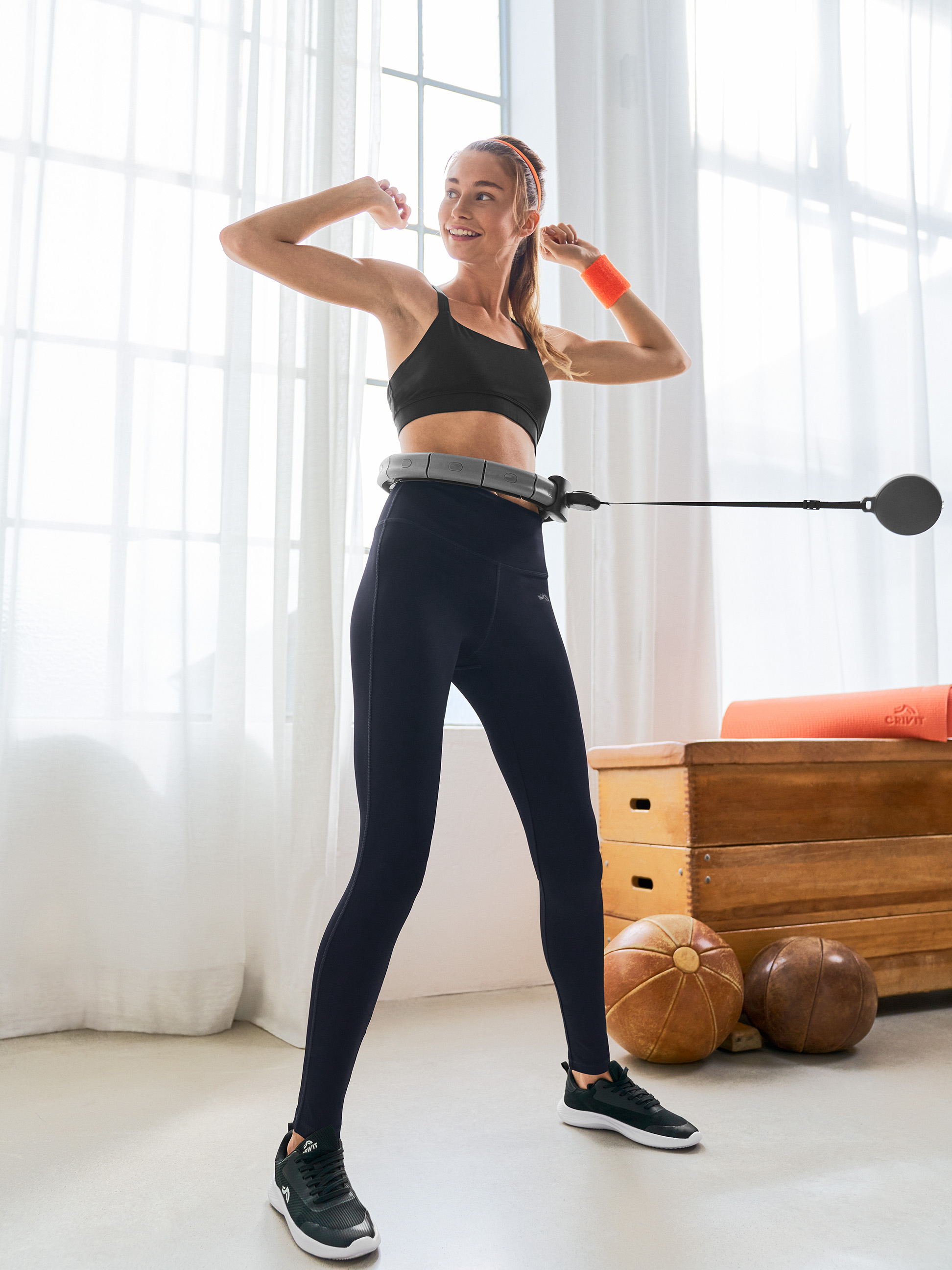 Frau in Crivit Sport-BH und Leggings benutzt einen Smart Hula Hoop