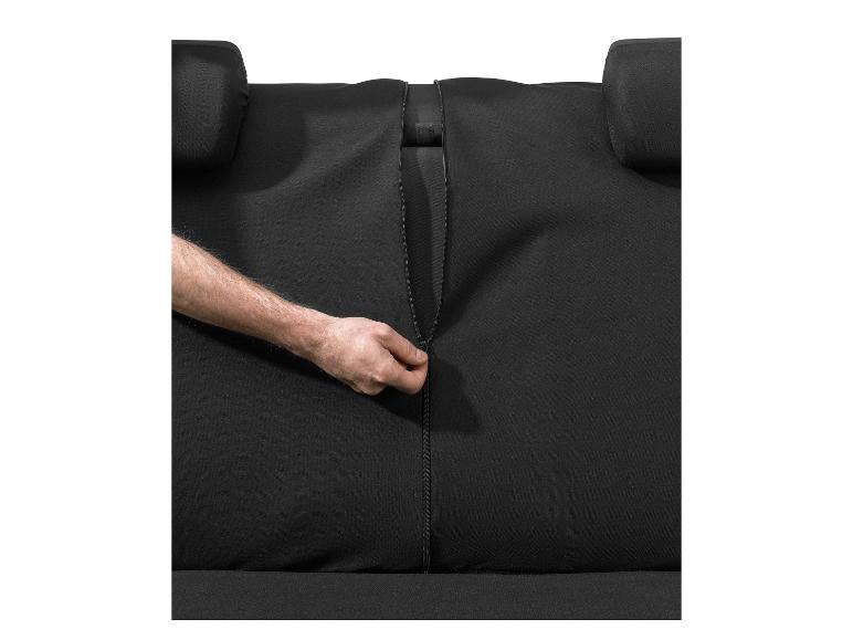 Hand schließt Reißverschluss eines schwarzen Autositzbezugs