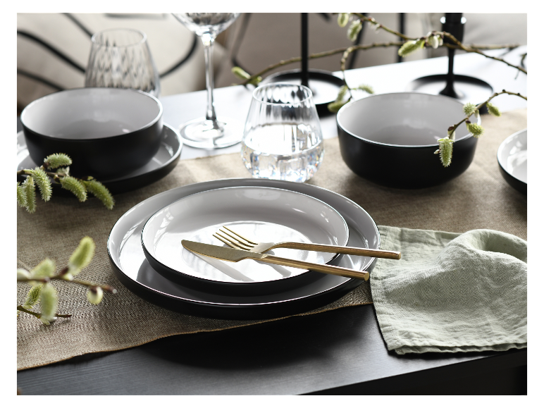 Schwarz-weißes Geschirr, goldenes Besteck, minimalistischer Stil.