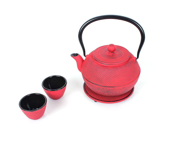 Eine rote Gusseisen-Teekanne mit zwei Tassen.