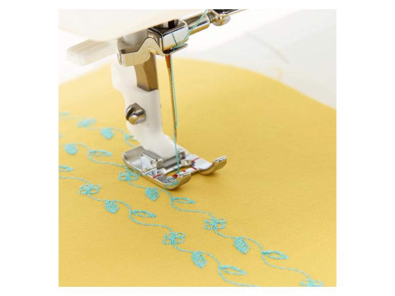 Nähmaschine stickt blaues Blumenmuster auf gelben Stoff