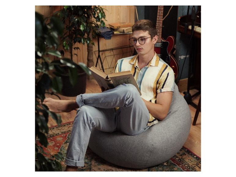Ein Mann liest in einem Sessel ein Buch.