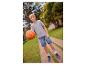 Junge in grauem T-Shirt und Jeans-Shorts hält einen Basketball auf einem Weg.