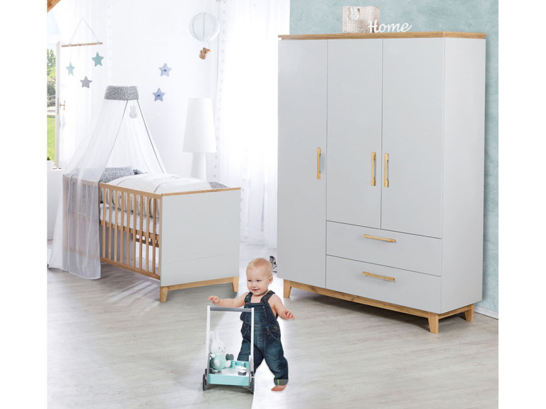 Babyzimmer mit weißer Wiege, Kleiderschrank und einem Kind, das einen Laufwagen schiebt.