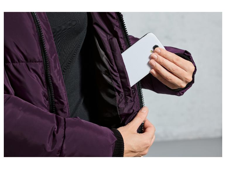 Eine Frau steckt ihr Handy in die Tasche einer lila Jacke.