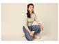 Frau in beigem Langarmshirt und weiter Jeans, hockend.