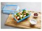 Blaue Frischhaltedose mit Brokkoli- und Süßkartoffelsalat mit Feta, Salz und Pfeffer.