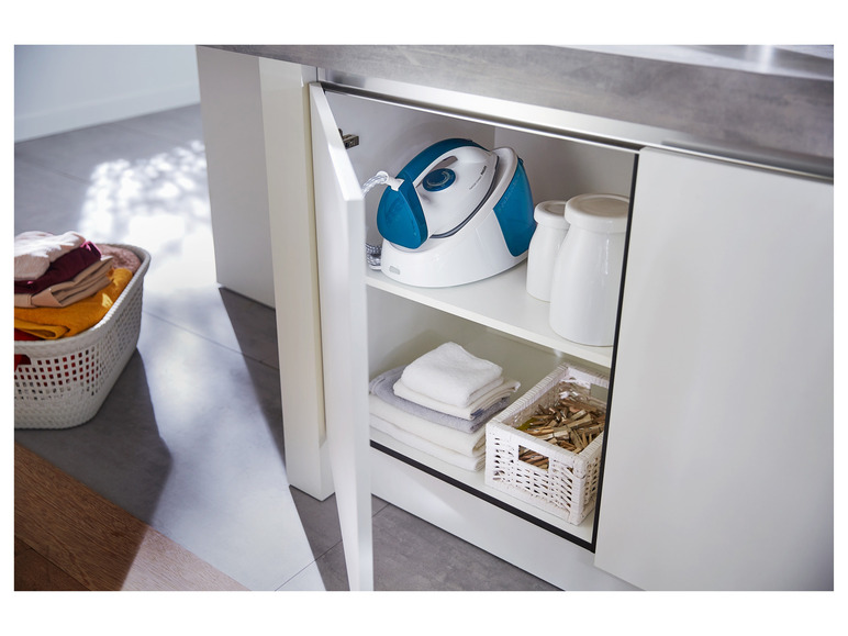 Ein offener Küchenschrank mit einem Philips Dampfbügeleisen, Handtüchern und Wäscheklammern.