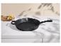 Schwarze Gusseisenpfanne auf einer weißen Marmorarbeitsplatte mit Kartoffeln und Knoblauch.
