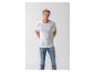 Mann in weißem T-Shirt mit Text und blauen Jeans, Hände hinter dem Rücken.