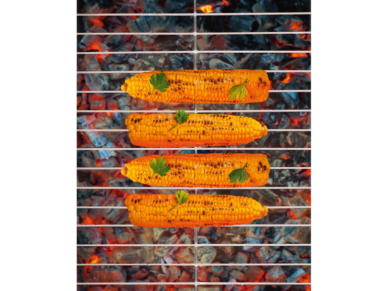 Vier gegrillte Maiskolben auf einem Grillrost über glühenden Kohlen.