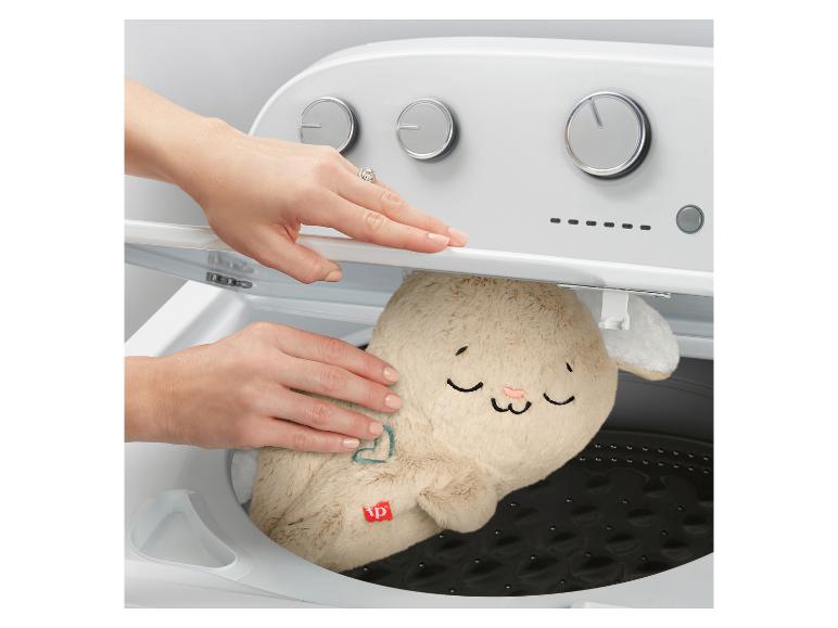 Eine Person legt ein Plüschkaninchen in eine Waschmaschine.