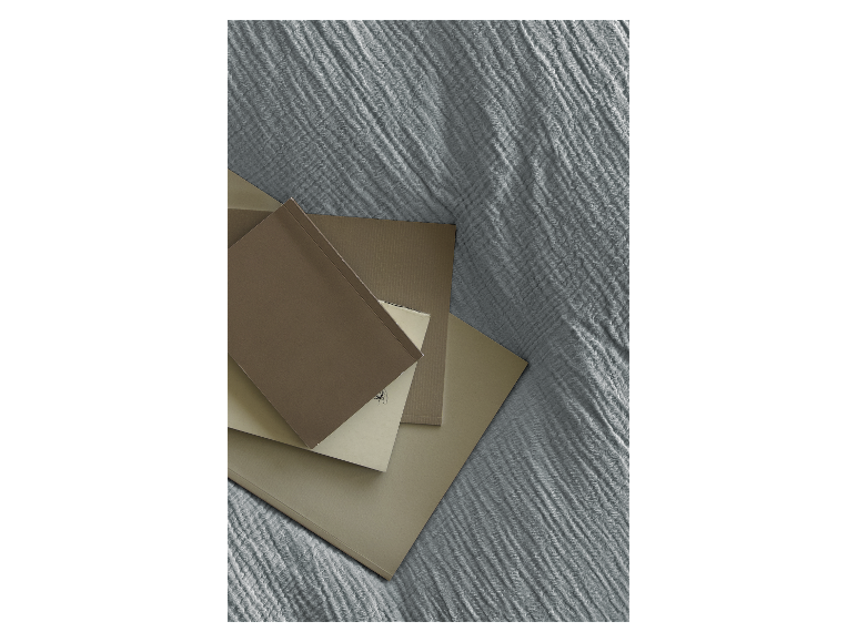 Beige und braune Notizbücher und Blöcke auf einem strukturierten Stoff gestapelt.