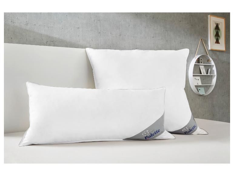 Zwei weiße Balette Kissen mit 135-Jahre-Jubiläumslogo auf einem Bett.