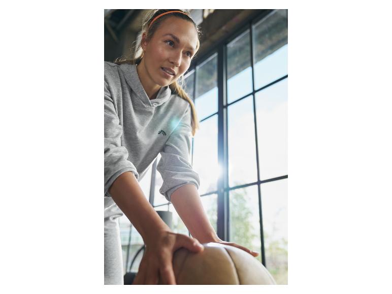 Frau in grauem Hoodie mit Gymnastikball.