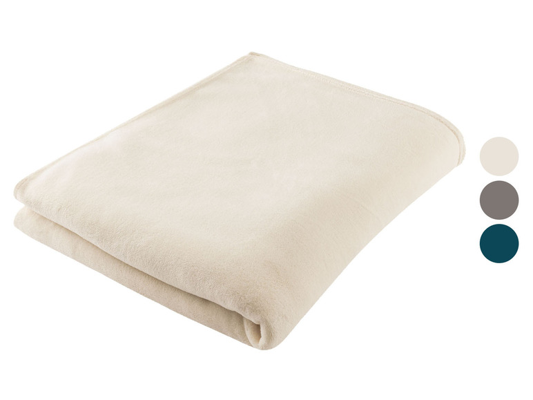 Eine weiche cremefarbene Decke, die auf einem weißen Hintergrund gefaltet ist.