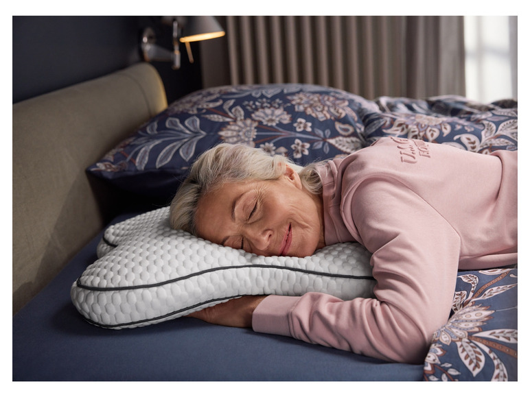 Eine Frau schläft auf einem Kissen mit Wabenmuster und einem blauen Bezug.