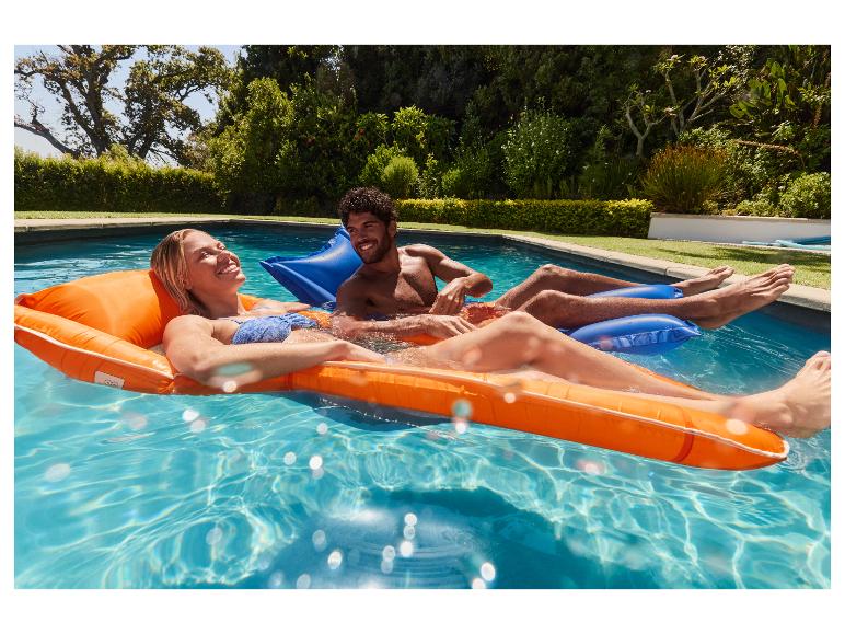 Paar entspannt auf orangefarbenen und blauen Pool-Schwimmhilfen im Pool.