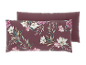 Zwei burgunderrote Kissen, eines mit einem Blumenmuster aus weißen und rosa Magnolien und grünen Blättern.